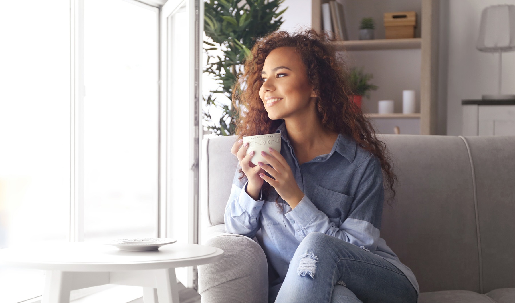 Girl sitting with her coffee looking out a window